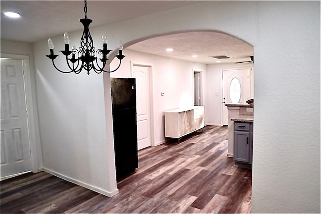 kitchen featuring gray cabinetry, black fridge, decorative light fixtures, a chandelier, and dark hardwood / wood-style flooring