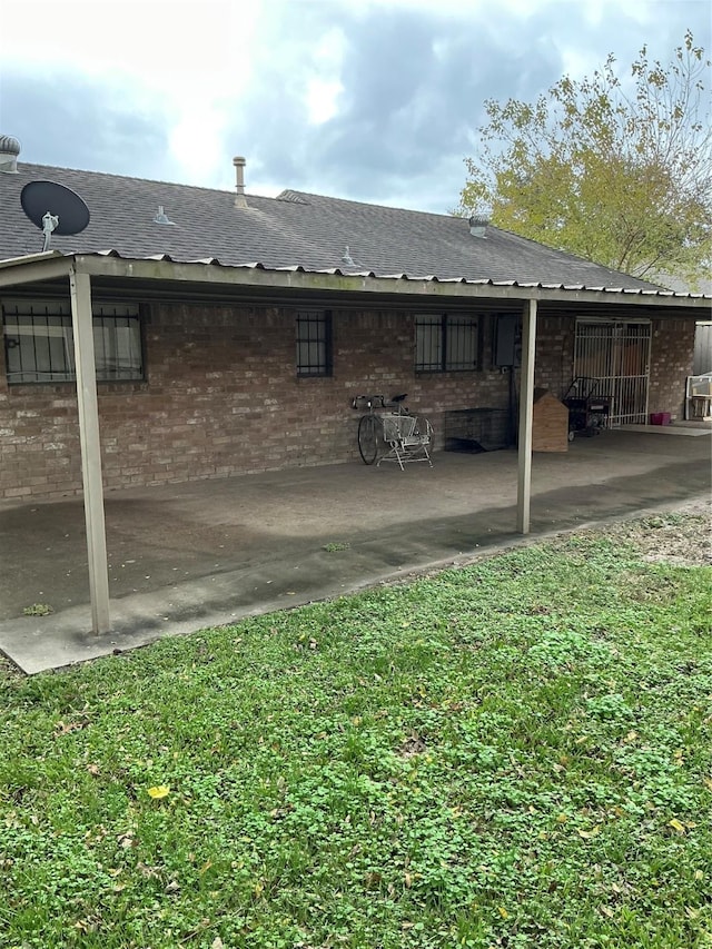 rear view of house with a patio area, a lawn, and brick siding