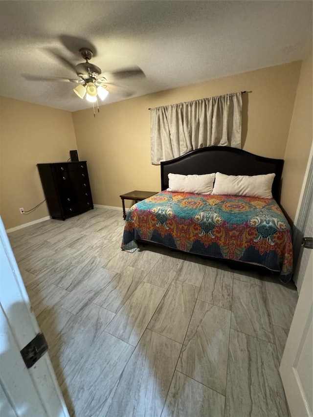 bedroom featuring ceiling fan, a textured ceiling, and baseboards