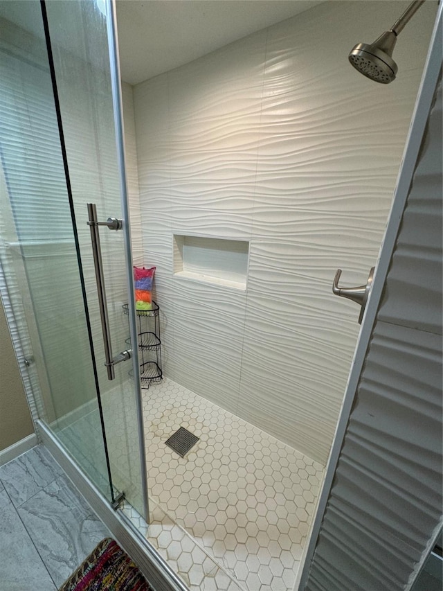 bathroom with marble finish floor and a shower stall