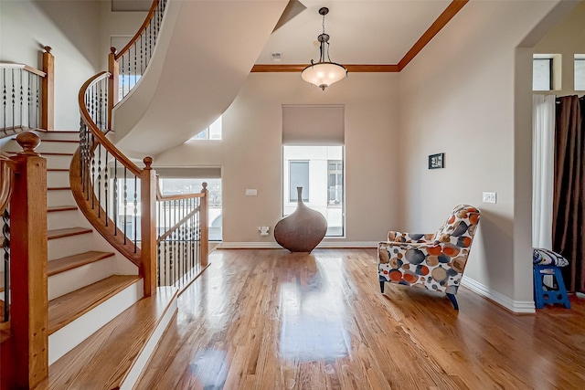 foyer entrance featuring hardwood / wood-style floors, a towering ceiling, and ornamental molding