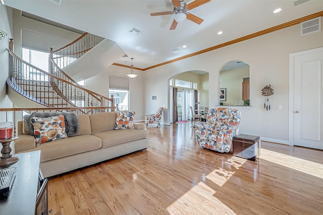 living room with ceiling fan, a healthy amount of sunlight, light hardwood / wood-style floors, and crown molding