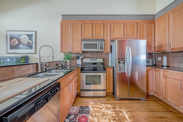 kitchen featuring light brown cabinetry, backsplash, stainless steel appliances, sink, and light hardwood / wood-style floors