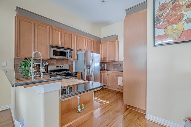 kitchen featuring sink, stainless steel appliances, backsplash, light brown cabinetry, and light wood-type flooring