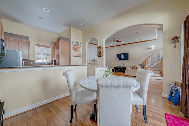 dining room featuring ceiling fan, light wood-type flooring, and sink