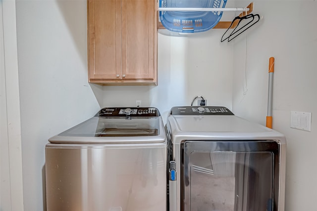 clothes washing area with cabinets and separate washer and dryer