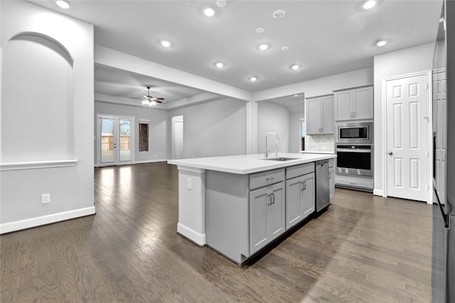 kitchen featuring gray cabinetry, stainless steel appliances, sink, dark hardwood / wood-style floors, and an island with sink