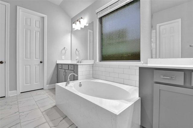 bathroom featuring a tub to relax in, vanity, and vaulted ceiling