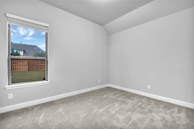 empty room with carpet floors and vaulted ceiling