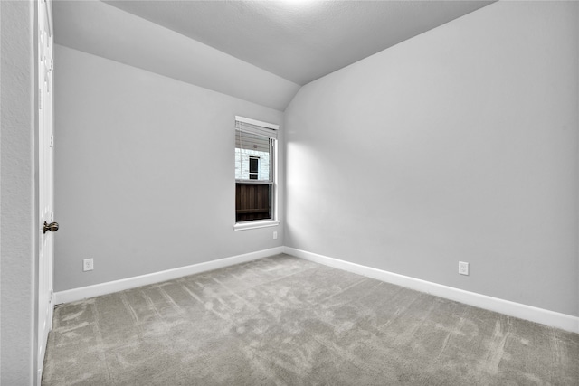 unfurnished room with lofted ceiling and light carpet