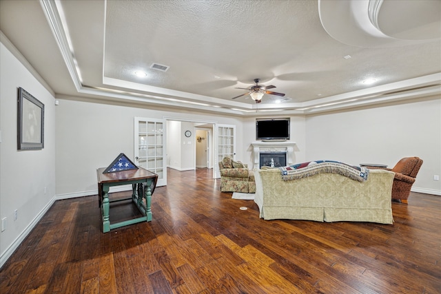 living room with a tray ceiling, a textured ceiling, and dark hardwood / wood-style floors