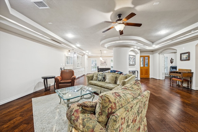 living room featuring ceiling fan, dark hardwood / wood-style floors, crown molding, a textured ceiling, and a tray ceiling