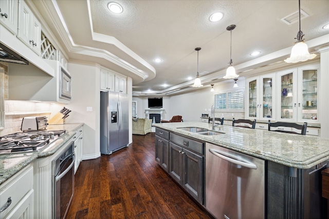 kitchen featuring sink, hanging light fixtures, a kitchen island with sink, white cabinets, and appliances with stainless steel finishes