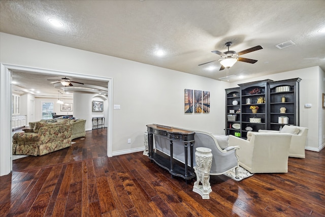 living room with ceiling fan, dark hardwood / wood-style flooring, and a textured ceiling