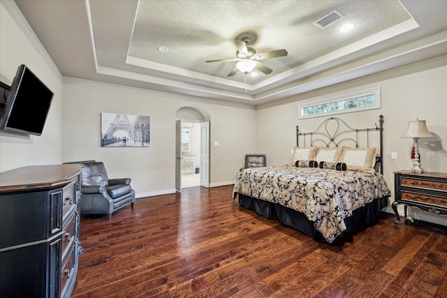 bedroom with a tray ceiling, ceiling fan, and dark wood-type flooring