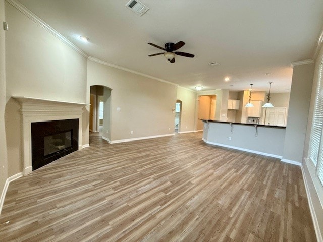 unfurnished living room with crown molding, ceiling fan, and light hardwood / wood-style floors