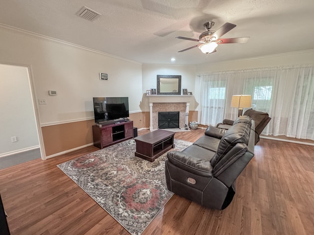 living room with wood-type flooring, a textured ceiling, ceiling fan, and crown molding