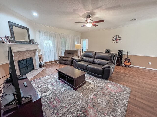 living room with a textured ceiling, hardwood / wood-style flooring, ceiling fan, and crown molding