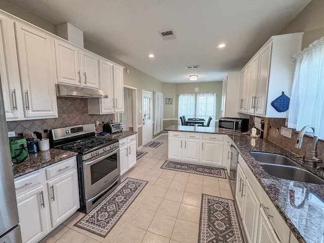 kitchen featuring white cabinets, sink, decorative backsplash, appliances with stainless steel finishes, and kitchen peninsula