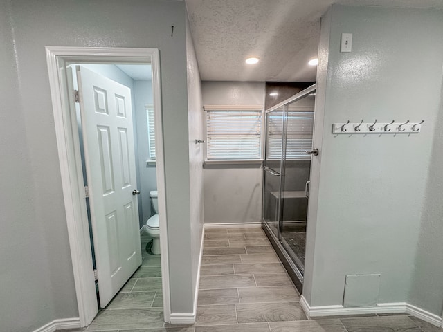 bathroom with walk in shower, a textured ceiling, and toilet