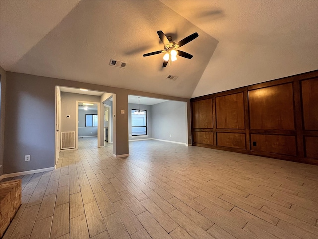 unfurnished living room with ceiling fan and vaulted ceiling