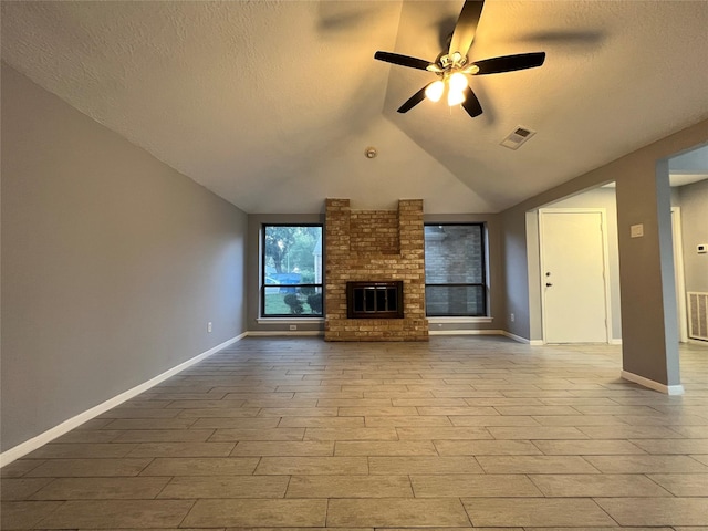 unfurnished living room featuring ceiling fan, lofted ceiling, a textured ceiling, and a brick fireplace