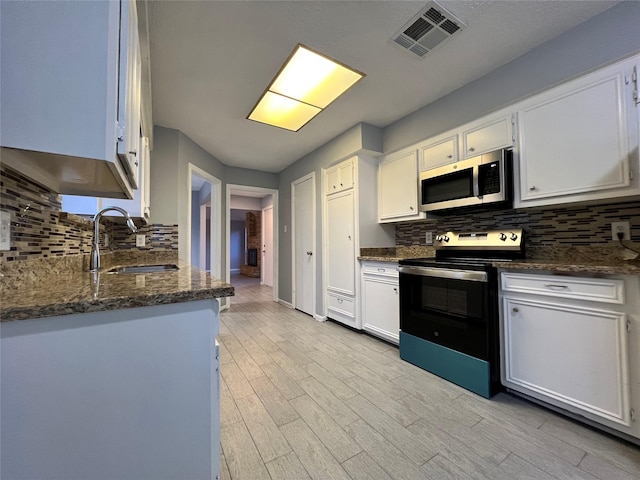 kitchen featuring dark stone counters, sink, white cabinets, and stainless steel appliances