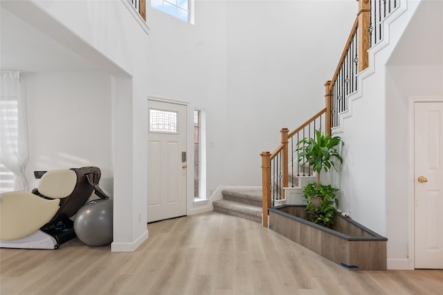 entrance foyer featuring a towering ceiling and light hardwood / wood-style floors