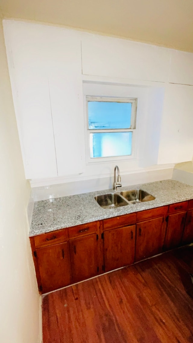 kitchen featuring light stone countertops, wood-type flooring, and sink