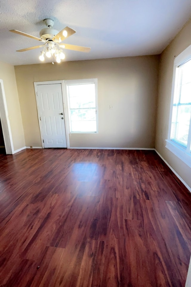 unfurnished room with a wealth of natural light, ceiling fan, and dark hardwood / wood-style floors