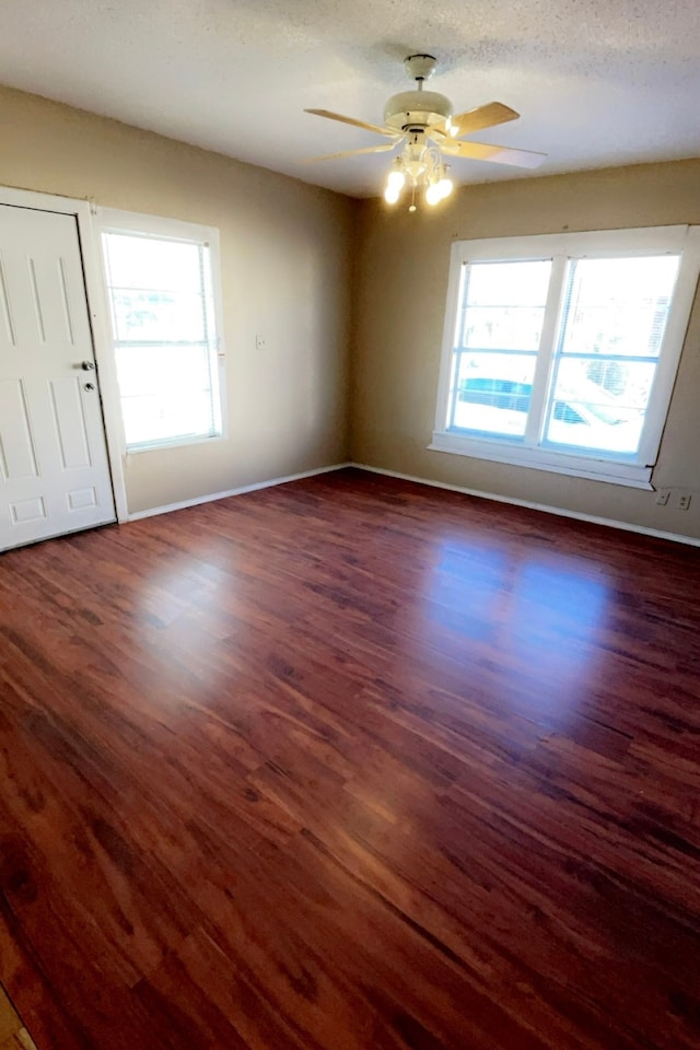 empty room featuring dark hardwood / wood-style floors, ceiling fan, and a textured ceiling