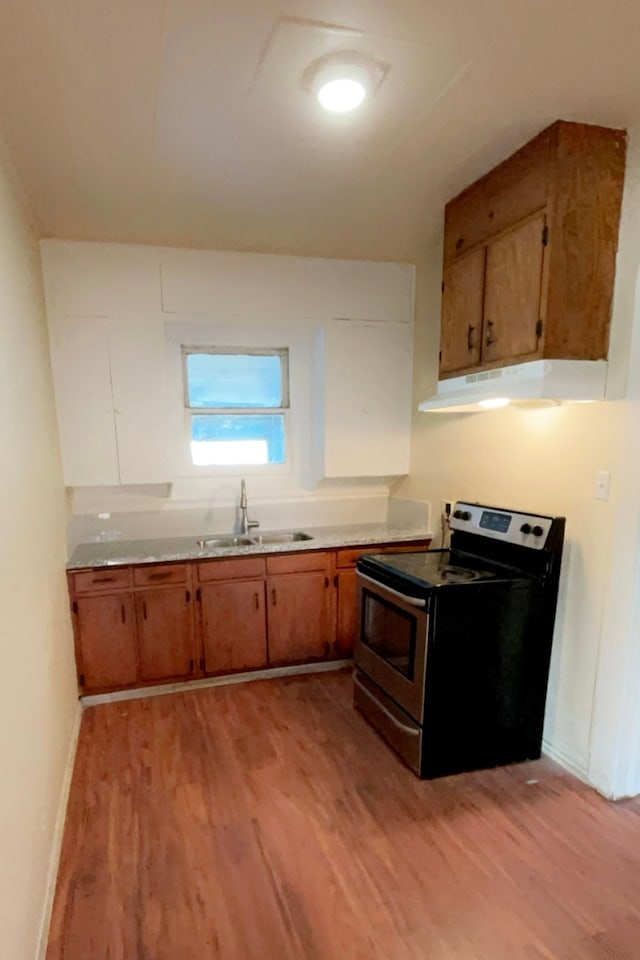 kitchen featuring black electric range oven, light wood-type flooring, and sink