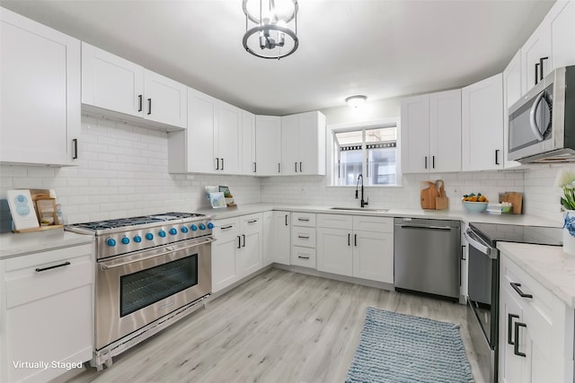 kitchen with appliances with stainless steel finishes, light hardwood / wood-style floors, white cabinetry, and sink