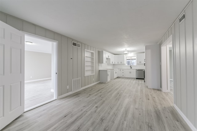 unfurnished living room featuring built in shelves, light hardwood / wood-style floors, and sink