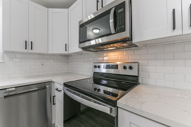 kitchen with light stone counters, white cabinets, and appliances with stainless steel finishes