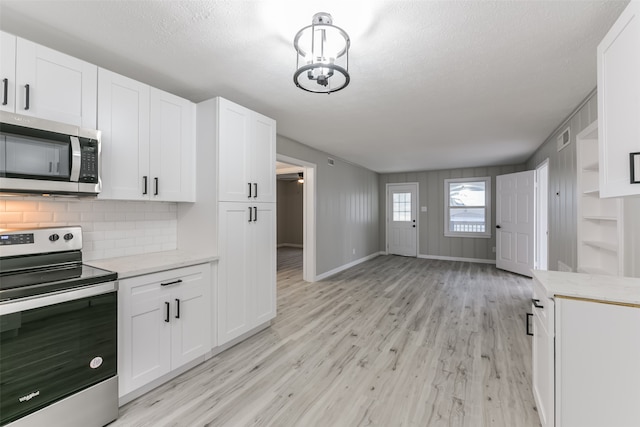 kitchen featuring appliances with stainless steel finishes, light wood-type flooring, tasteful backsplash, and white cabinetry