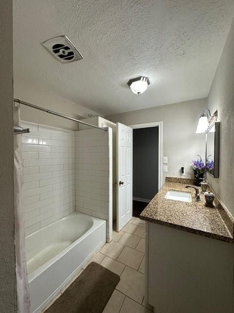 bathroom featuring tile patterned flooring, vanity, tiled shower / bath combo, and a textured ceiling