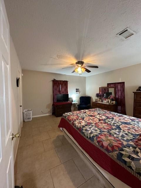 bedroom with tile patterned floors, ceiling fan, and a textured ceiling