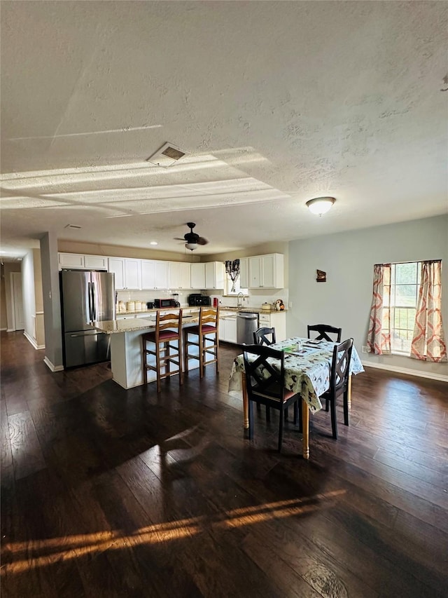 dining space featuring a textured ceiling, dark hardwood / wood-style floors, and ceiling fan