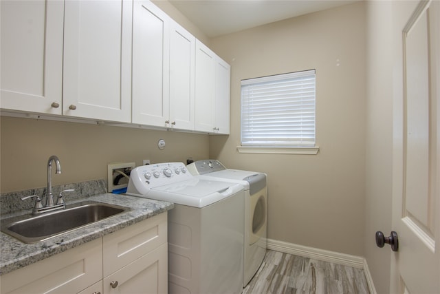 laundry area featuring cabinets, washing machine and dryer, light hardwood / wood-style flooring, and sink