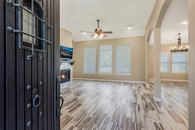 unfurnished living room featuring ceiling fan with notable chandelier and hardwood / wood-style flooring