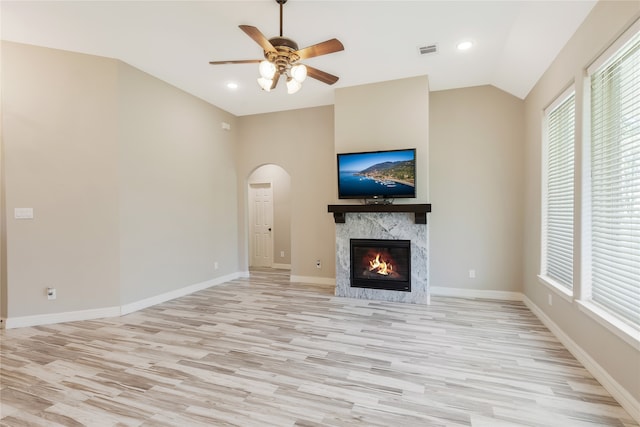 unfurnished living room featuring a premium fireplace, light hardwood / wood-style flooring, ceiling fan, and lofted ceiling