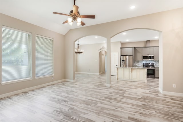 unfurnished living room featuring ceiling fan with notable chandelier, light hardwood / wood-style flooring, and lofted ceiling