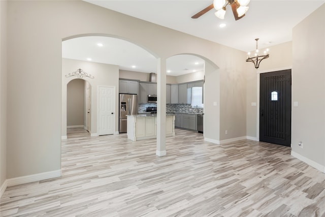 interior space with ceiling fan with notable chandelier and light wood-type flooring