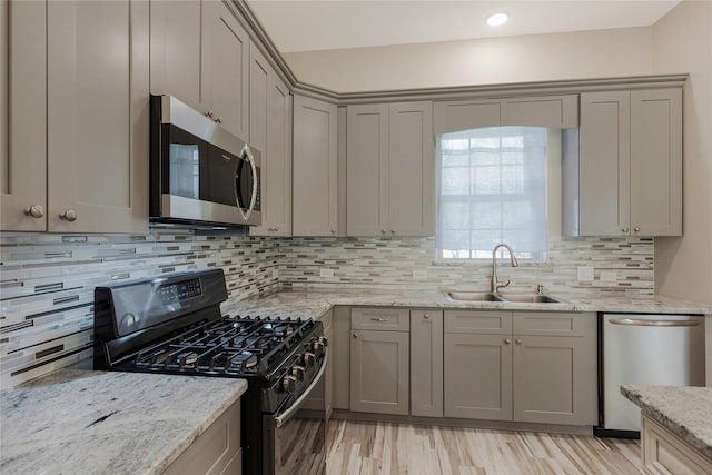 16979 Concord Dr, Conroe, TX 77385 - kitchen featuring stainless steel appliances, gray cabinets, a sink, light stone countertops, and decorative backsplash