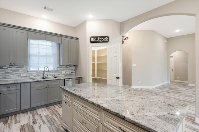 16979 Concord Dr, Conroe, TX 77385 - kitchen featuring a sink, arched walkways, gray cabinetry, backsplash, and dishwasher