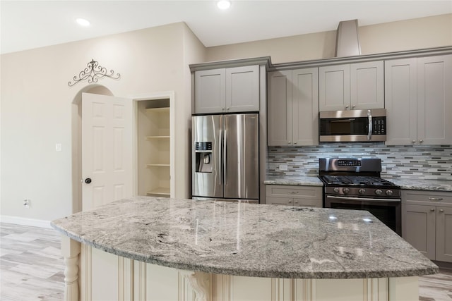 16979 Concord Dr, Conroe, TX 77385 - kitchen with stainless steel appliances, gray cabinetry, a center island, decorative backsplash, and light wood-style flooring