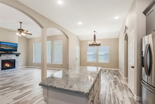 kitchen with light stone countertops, stainless steel fridge, vaulted ceiling, and plenty of natural light