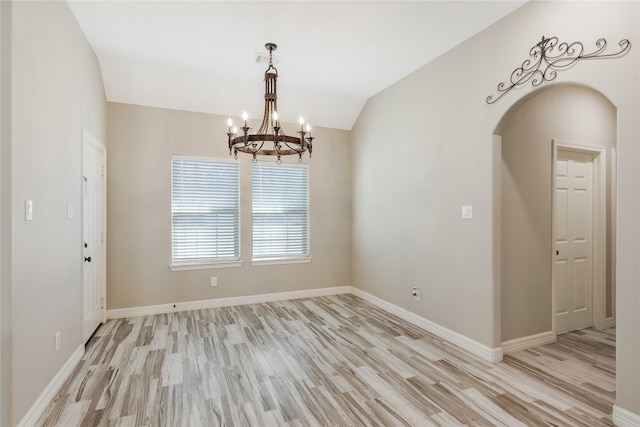 empty room featuring light wood-type flooring, lofted ceiling, and a notable chandelier