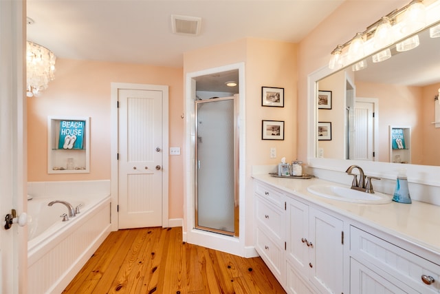 bathroom featuring wood-type flooring, vanity, an inviting chandelier, and separate shower and tub